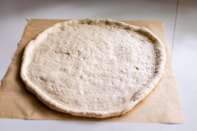pizza dough rolled out on a piece of parchment paper