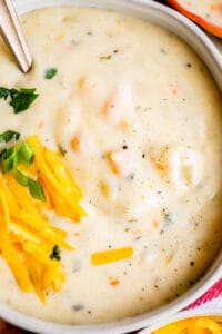 homemade potato soup in a white bowl with cheese garnish