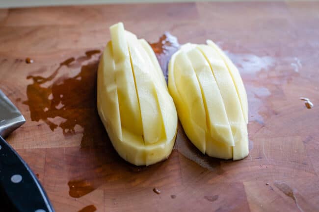 a large russet potato cut into strips on a cutting board.