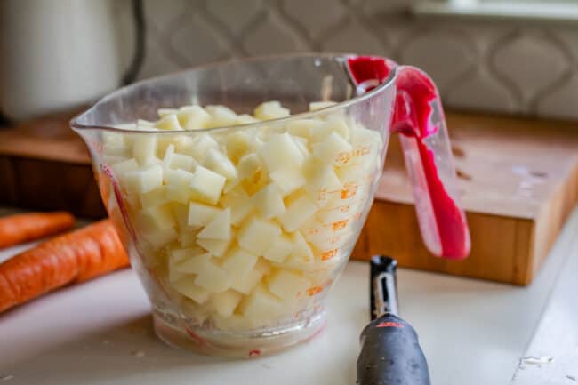 chopped russet potato in a measuring cup on a counter.