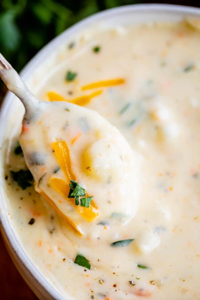 potato soup on a spoon with cheese and parsley.