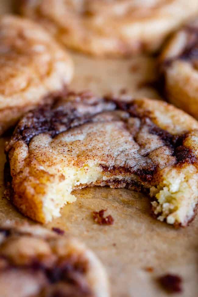 soft cinnamon roll cookie with cinnamon swirls with a bite taken out of one.