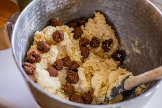 snickerdoodle dough in a stand mixer bowl with cinnamon roll filling balls mixed in