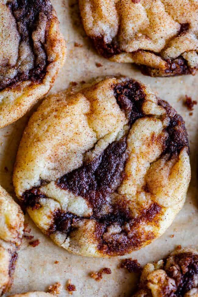 soft cinnamon roll cookies with cinnamon swirl on parchment paper.