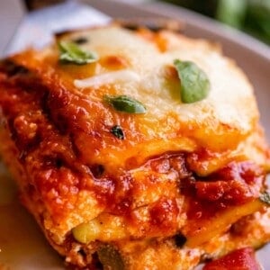 zucchini lasagna on a plate with fork, topped with basil