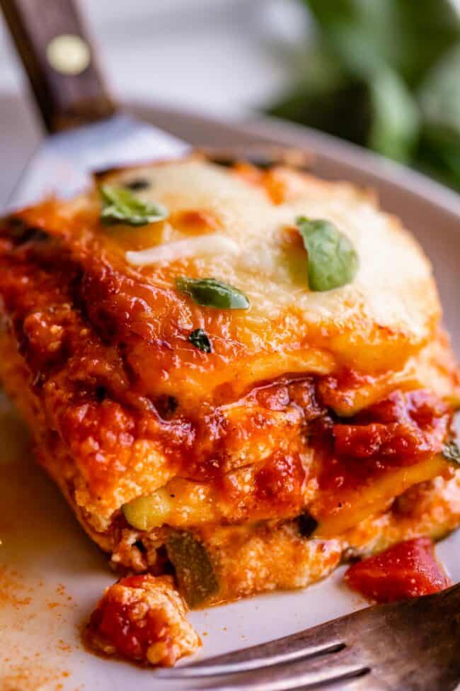 zucchini lasagna on a plate with fork, topped with basil