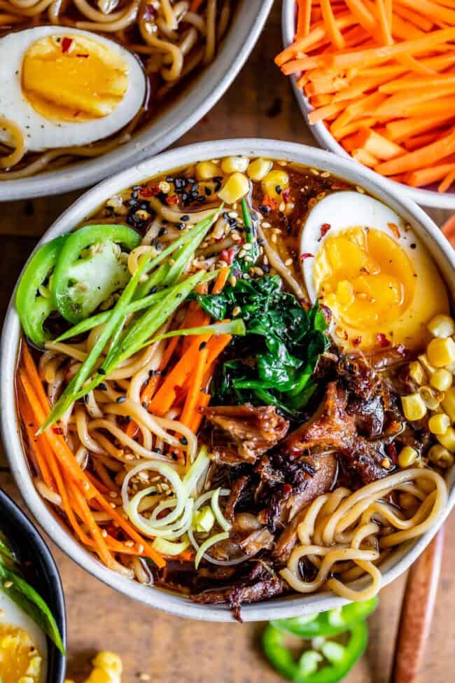 pork ramen broth in a bowl with pork, eggs, carrots, etc