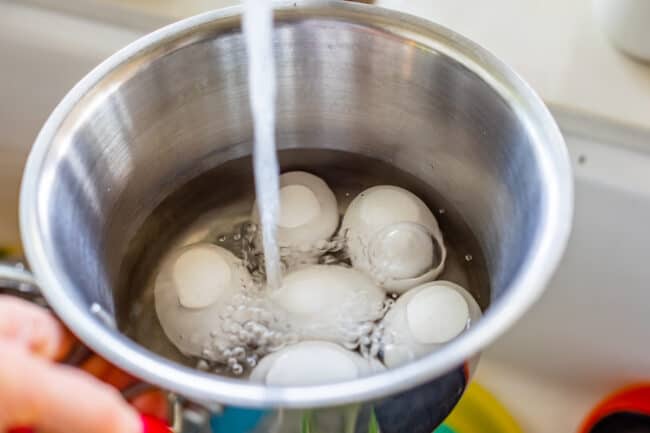 adding water from a faucet into a pot with eggs