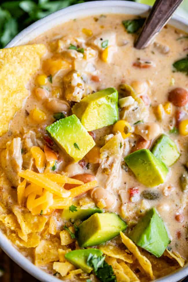easy white chicken chili close up in a bowl with tortilla chips and avocado