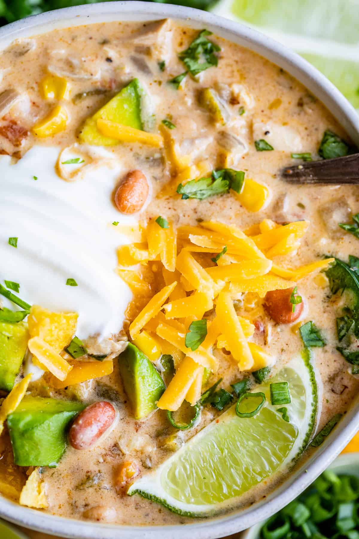 white bean chicken chili in a white bowl with lime and cheese garnish