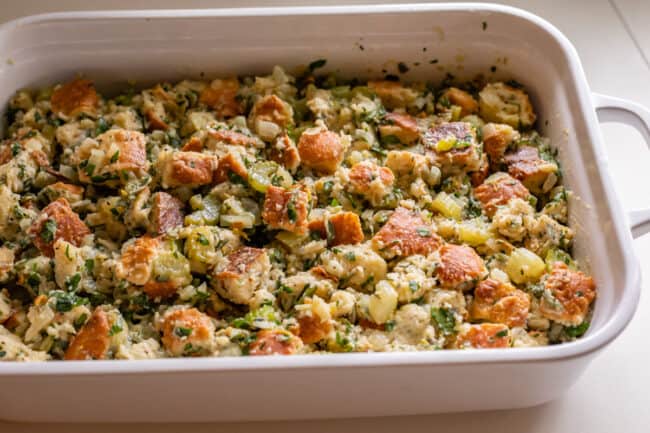 raw stuffing spread out in a white casserole dish