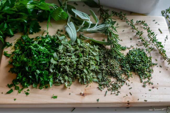parsley, sage, rosemary and thyme shopped on a cutting board
