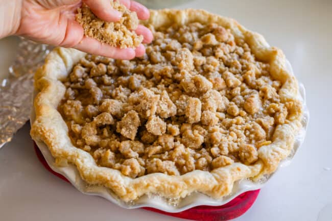 adding more streusel crumb topping to half baked pie.