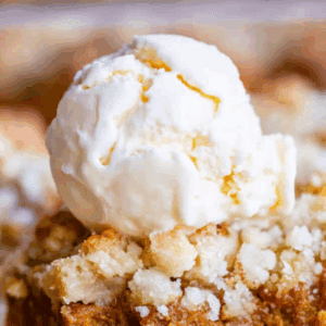 A close-up of pumpkin pie bars topped with a scoop of vanilla ice cream, highlighting the crumbly crust and creamy pumpkin filling.