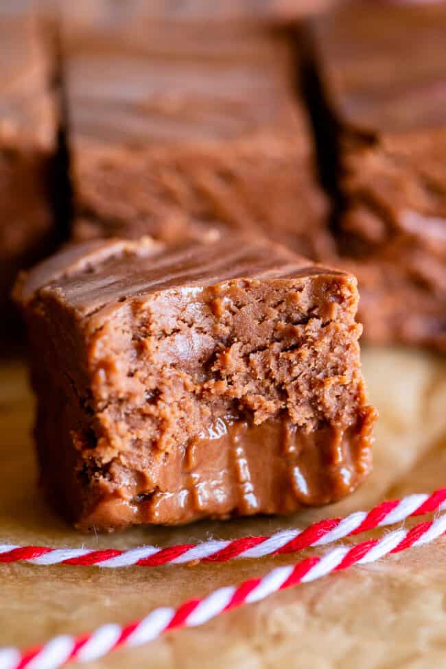 fudge recipe with marshmallow fluff, with a bite taken out and red and white string on parchment paper.