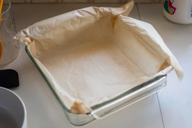 a square glass pan lined with brown parchment paper