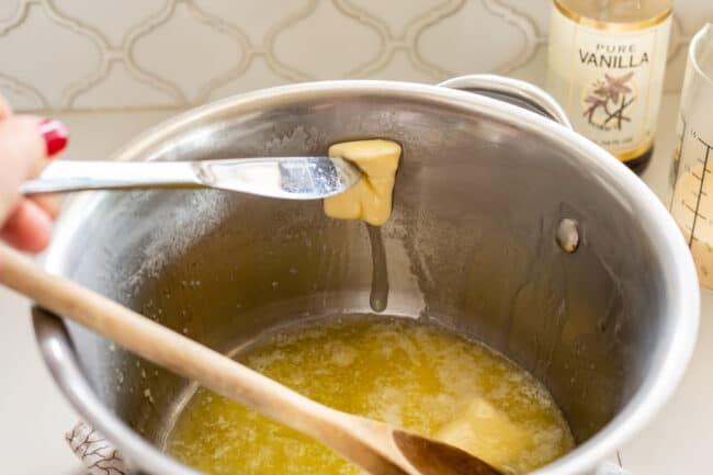 greasing the edge of a pot with melting butter using a knife
