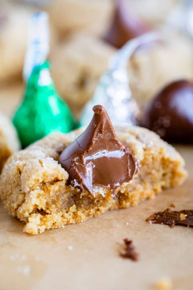 peanut butter kiss cookie with bite taken out and more Hershey's kisses in the background.