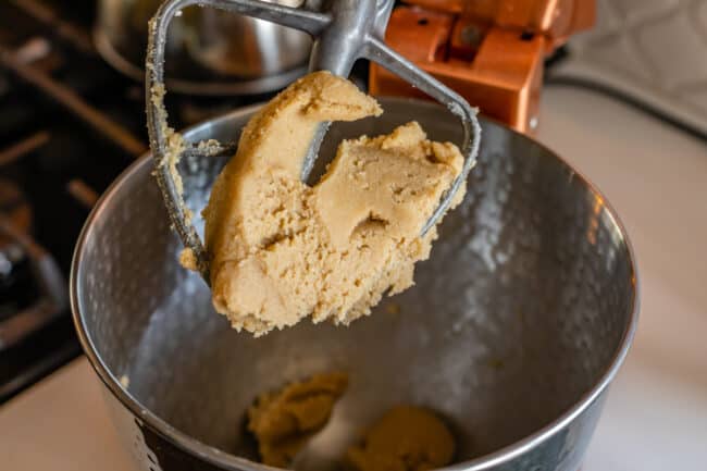 butter, sugar, and peanut butter mixed together in the bowl of a stand mixer.