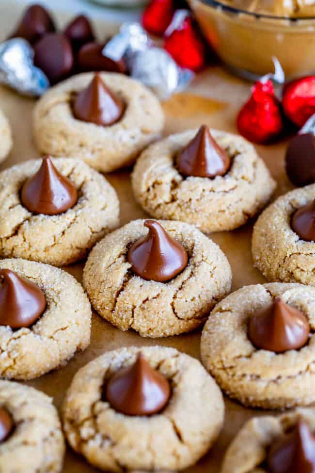 peanut butter blossom cookies with Hershey's kisses and peanut butter in the background.