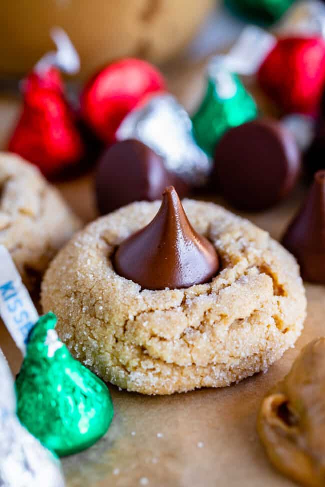 peanut butter blossom cookie with Hershey's Kisses in the background.