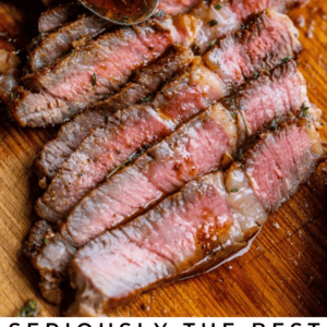 Sliced, medium-rare ribeye steak on a wooden board, drizzled with savory sauce from a spoon and garnished with fresh herbs. Text below reads: Seriously the Most Flavorful Ribeyes You’ll Ever Have – The Food Charlatan.