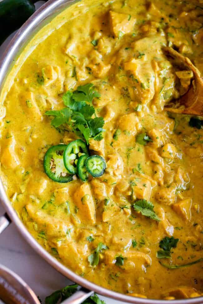 chicken curry recipe in a pan topped with jalapeno and cilantro.