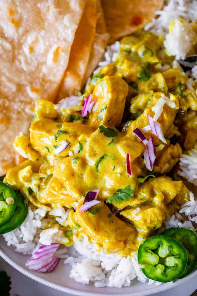 Indian chicken curry piled on top of rice on a plate with roti.