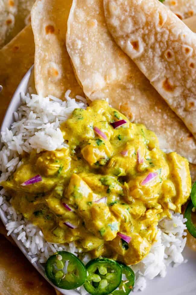 chicken curry on top of rice garnished with jalapenos and red onions and roti