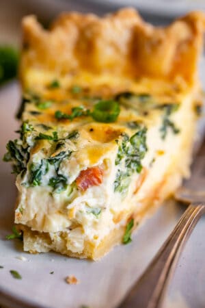spinach quiche on a plate with a bite taken out