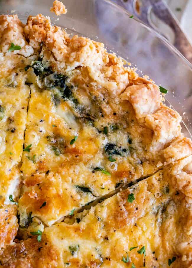 overhead shot of a slice of spinach quiche in a glass pie pan.