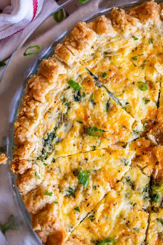 overhead slice of ham and cheese quiche with pie crust and green onions