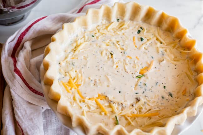 unbaked quiche in pie shell with white and red napkin.