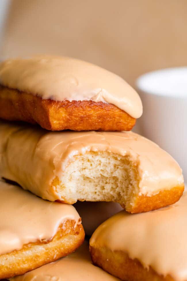 bite taken out of donut in stack of maple bars