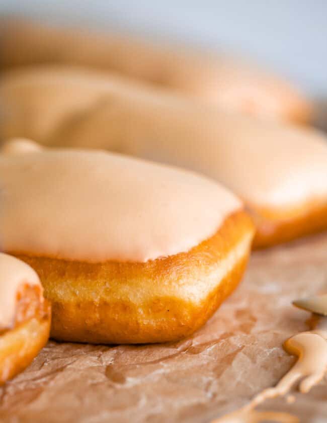 maple donut lined up with others on parchment paper