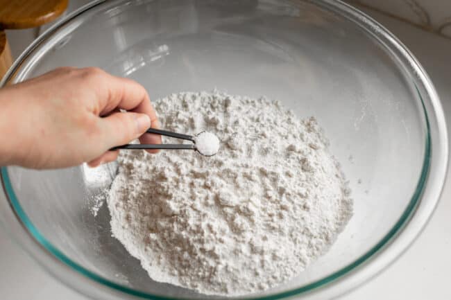 adding salt to a large bowl of bread flour