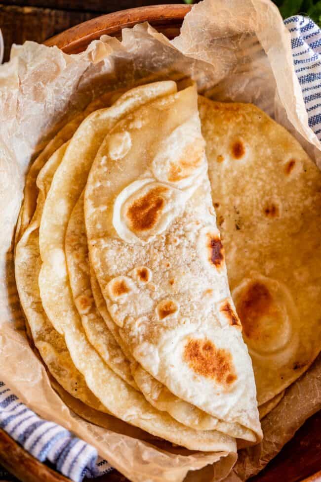 roti bread stacked in a wooden bowl with parchment paper