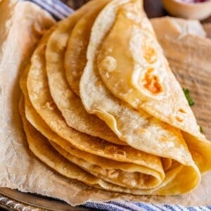 Indian roti bread on a metal plate with blue napkin and parchment paper