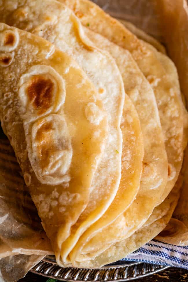 Indian bread stacked and folded over on a metal plate with blue napkin