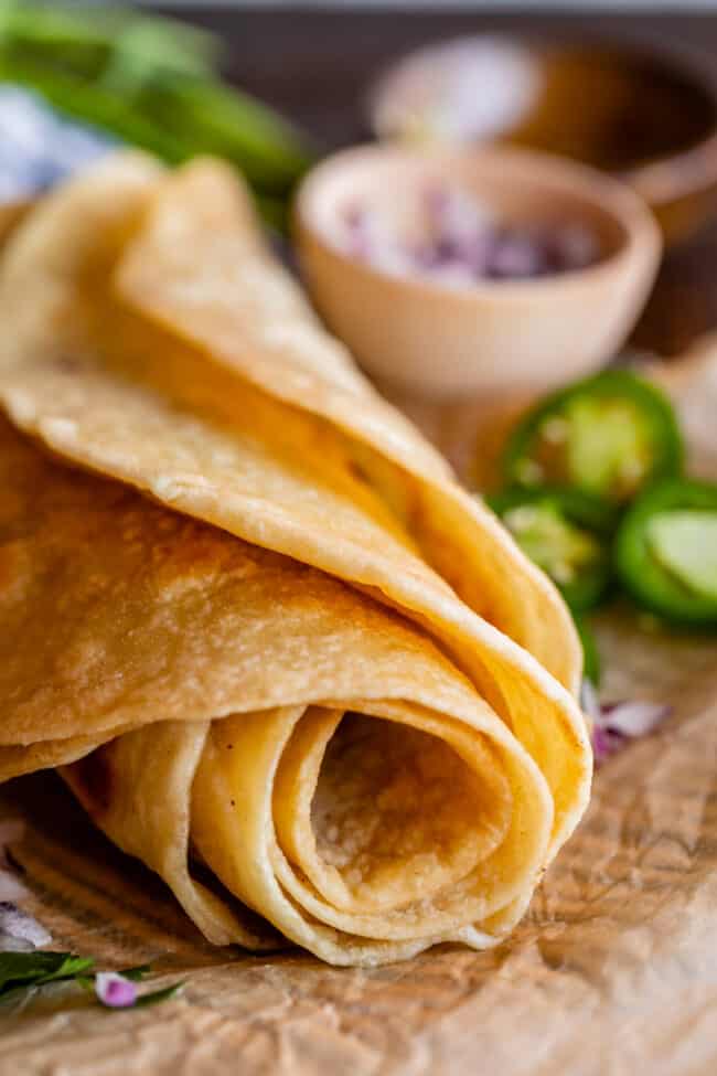 rolled up indian roti flatbread on parchment paper with jalapeno and red onion