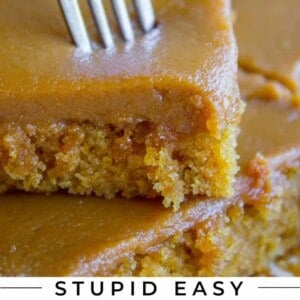 caramel cake stacked on another piece, with a fork taking a bite
