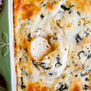 bread slice scooped into center of pan of spinach artichoke dip recipe