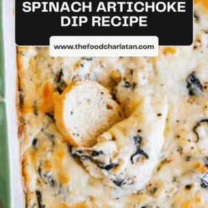 A close-up of creamy spinach artichoke dip baked in a casserole dish, topped with golden melted cheese and a round slice of bread. Text overlay reads Spinach Artichoke Dip Recipe, highlighting this classic spinach artichoke dip favorite.