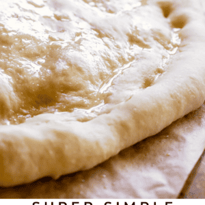 rising rolled-out pizza dough on a wooden cutting board.