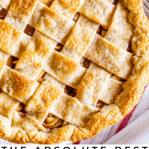 Top view of a golden, lattice-crust apple pie surrounded by fresh apples. Text at the bottom reads: The absolute favorite apple pie. The Food Charlatan.