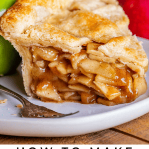 A close-up of a slice of homemade apple pie with a golden, flaky crust, gooey cinnamon apple filling, and a fork on a white plate. Fresh apples and a whole pie are in the background. Text reads: Homemade apple pie with cinnamon apples.