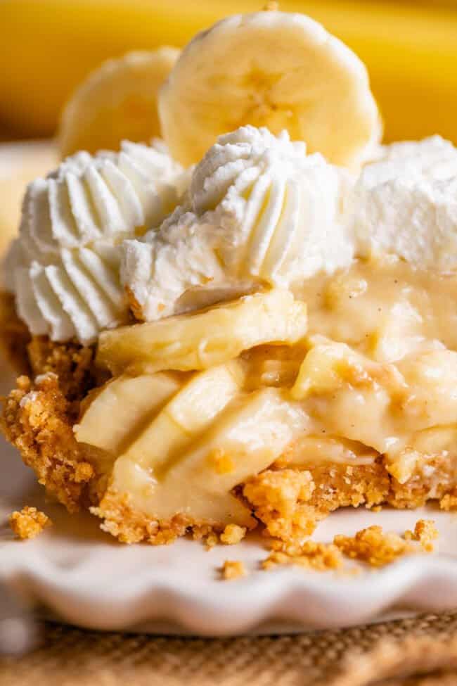 slice of easy banana cream pie on a plate topped with whipped cream.