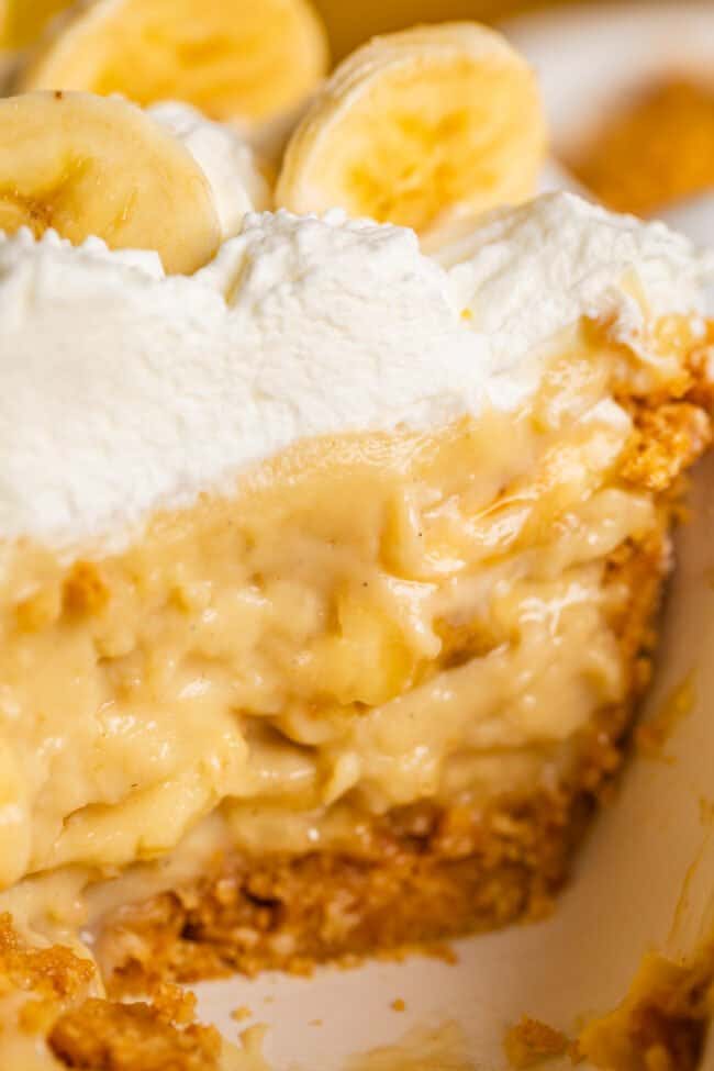 cross section slice of banana cream pie topped with cream and bananas.
