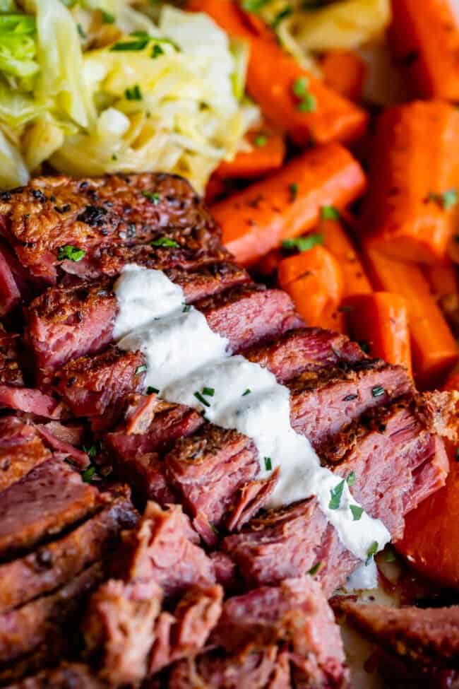 sliced slow cooker corned beef garnished with horseradish sauce