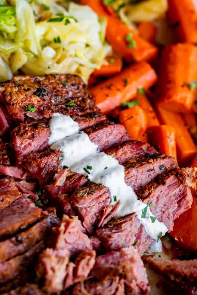 sliced slow cooker corned beef garnished with horseradish sauce.